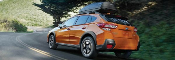 An orange 2018 Subaru Crosstrek driving up a mountainous road